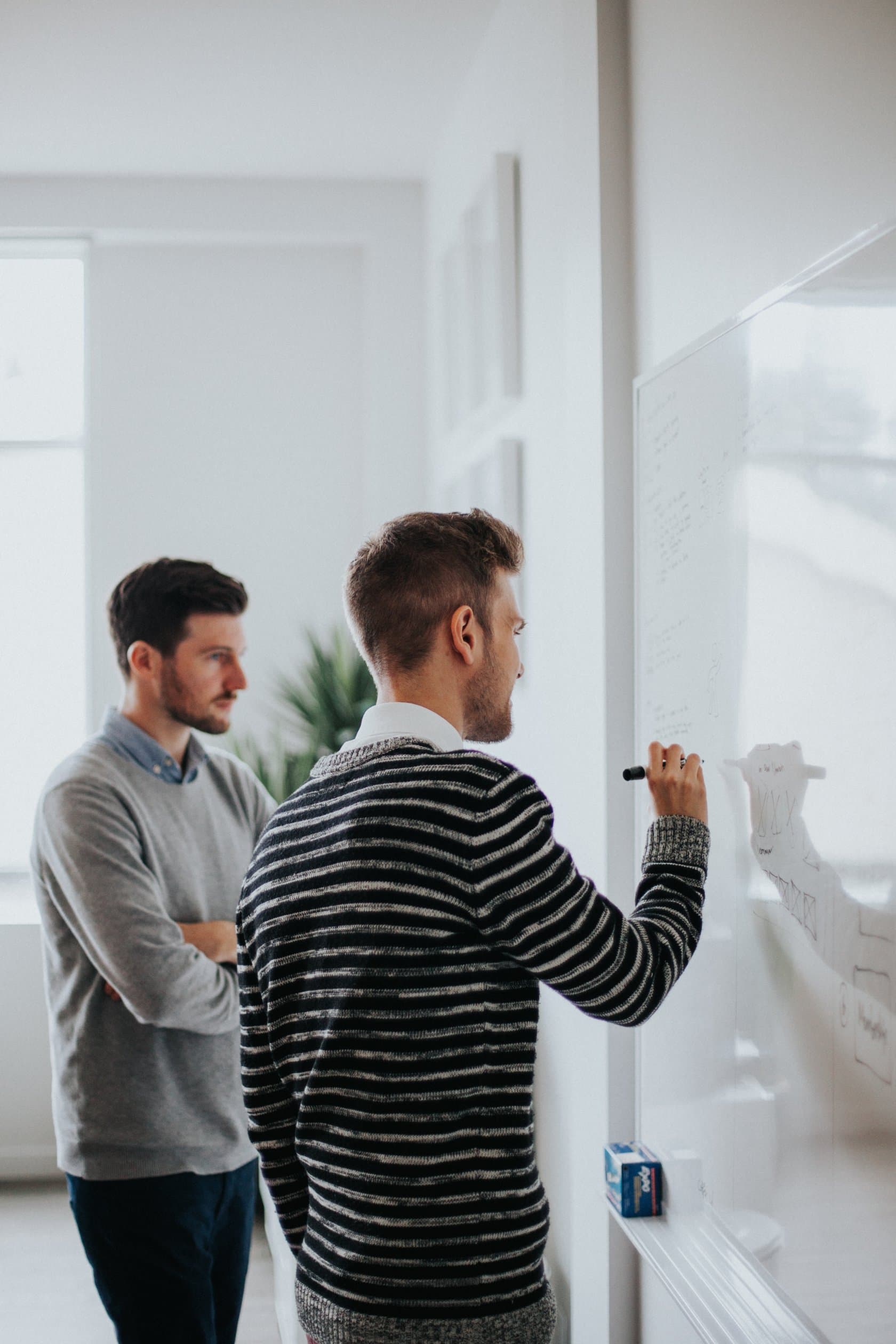 Two specialists discussing notes on a whiteboard